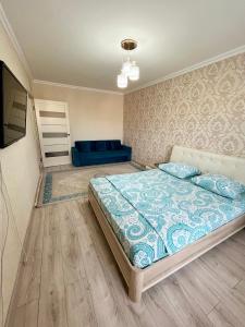 a bedroom with a large bed and a blue couch at Авангард 4-12 in Atyraū