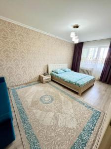 a bedroom with a bed and a rug at Авангард 4-12 in Atyraū