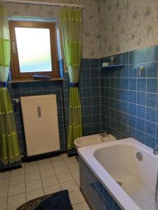 a blue tiled bathroom with a tub and a window at Villa Viola in Breitenstein +27 photos
