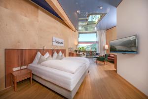 a bedroom with a large white bed and a tv at Der Erlhof Restaurant & Landhotel in Zell am See