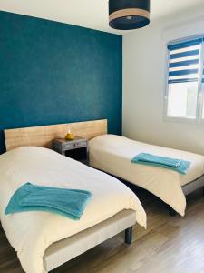2 letti in una camera da letto con parete con accento blu di "Les Pâturages" Chanas - Maison Entière proche A7, 2 Chambres, 4 Personnes, Jardin Privé, Piscine & BBQ a Chanas