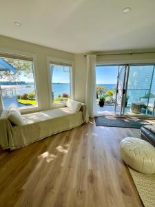 Nanoose BayにあるHigh Tide Suite - New Bright Oceanfront Escape with Spa-like Bathの大きなベッドと大きな窓が備わる広いベッドルーム1室が備わります。
