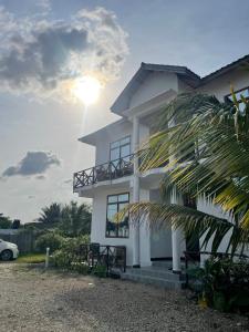キウェンワにあるAsili Nyumbani Residenceの太陽を背景にした白い家