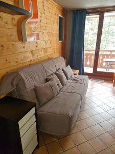 Un sofá en una sala de estar con una pared de madera. en Les Grenadines, en Les Deux Alpes