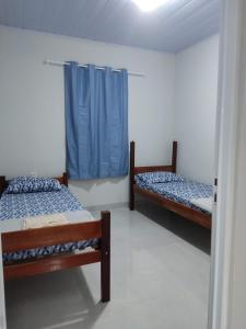 two beds in a room with blue curtains at Residencial Franco Casa 02 in Primavera do Leste