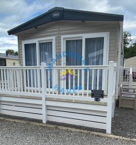 una pequeña casa con una valla blanca y un porche en Wanderers Haven, Brigham, Cockermouth, Cumbria, en Brigham