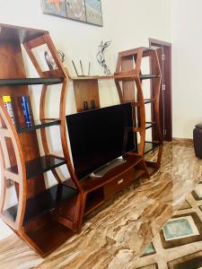 sala de estar con estanterías de madera y TV de pantalla plana en KIGALi LODGE APART, en Kigali