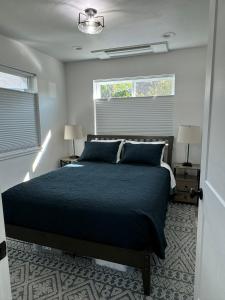 a bedroom with a black bed and two windows at Newer Cozy Guest Cottage with Saltwater Spa! in Weed