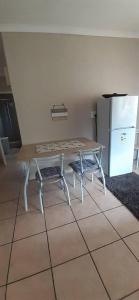 a table and a bench in a room with a refrigerator at Encome Guest house in Pongola