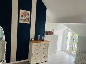 a bedroom with a dresser and a blue wall at Le Petit Bréhémontais in Bréhémont