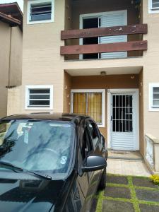 une voiture noire garée devant une maison dans l'établissement que delicia de lugar, à Itanhaém