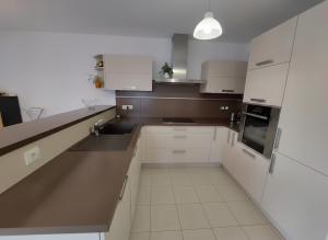 a white kitchen with white cabinets and a sink at Au cœur de St Jorioz, spacieux appartement avec terrasse et vue montagne. in Saint-Jorioz