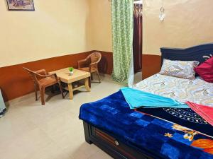New HampiにあるNew Siddharth homestay hampiのベッドとテーブルと椅子のある寝室 +8枚の写真