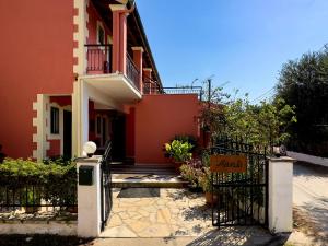 a red house with a gate and a fence at Marili Apartments in Roda