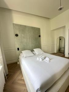 ein weißes Bett mit zwei weißen Handtüchern darauf in der Unterkunft Suite Brume - Maison les Arcades au pied de la gare de Charleville-Mézières in Charleville-Mézières + 2 Fotos