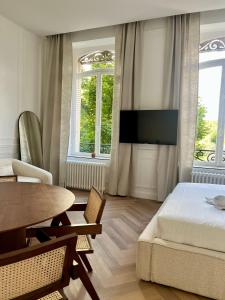 ein Schlafzimmer mit einem Bett, einem Tisch und einem Fernseher in der Unterkunft Suite Brume - Maison les Arcades au pied de la gare de Charleville-Mézières in Charleville-Mézières