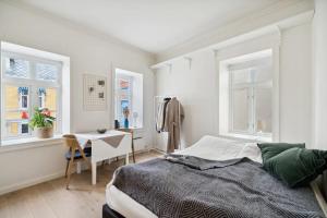 a bedroom with a bed and a table and windows at Central and modern in Tromsø