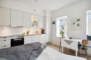 a kitchen with white cabinets and a table and a desk at Central and modern in Tromsø