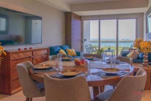 a dining room with a table with chairs and a couch at Condo Blue Lagoon Cancun-Espectacular Vista in Cancún