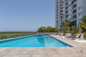 a swimming pool with chairs and a building at Condo Blue Lagoon Cancun-Espectacular Vista in Cancún