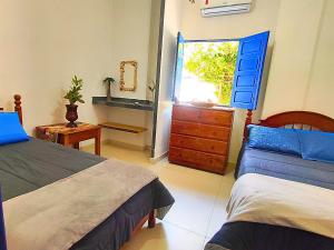 a bedroom with two beds and a dresser and a window at Morada da Praia - Porto de Pedras à Beira-Mar in Pôrto de Pedras