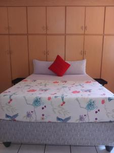 a bed with a red pillow on top of it at Yana Guest House in Polokwane