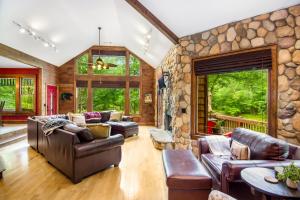 ein Wohnzimmer mit Ledermöbeln und einer Steinmauer in der Unterkunft Cabin Zen, Riverfront, Hot Tub, Arcades, Sleeps 8 in Ellijay