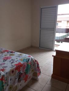 une chambre avec un lit recouvert d'une couverture fleurie dans l'établissement que delicia de lugar, à Itanhaém