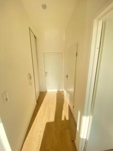 an empty hallway with a white door and a wooden floor at Appartement T2 cosy au calme in Épinay-sur-Orge