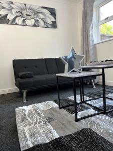 a living room with a black couch and a table at Home In Maidstone in Maidstone