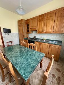 a kitchen with a green table and wooden cabinets at Domus Maris in Marina di Ascea +3 photos