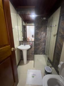 a bathroom with a sink and a shower and a toilet at Parque Orquídeas Hotel in Urrao