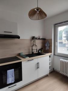 a kitchen with white cabinets and a sink and a window at Chaleureux T2 Centre Ville in Montbéliard