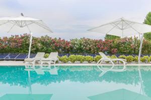 2 sillas blancas y sombrillas junto a una piscina en Villa Onofria, en Sirmione