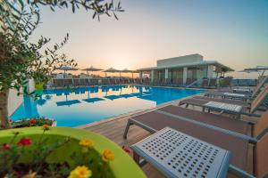 a swimming pool with chairs and a table and a building at Maritim Antonine Hotel & Spa in Mellieħa