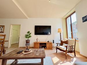 a living room with a table and a tv at L'Éclat des cimes I 105 m2 & centre ville in Le Bourg d'oisans
