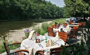 een rij tafels en stoelen naast een rivier bij Hôtel/Restaurant à la Ferme in Ferrières