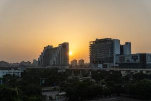 a city skyline with the sun setting behind buildings at Stylish & Comfortable Studio near Expo Center Greater Noida opposite Metro in Greater Noida