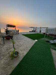 a beach with a bench and a table and grass at كرفان السرور على البحر in Half Moon Bay