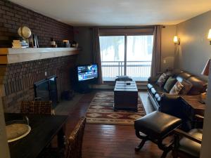 a living room with a couch and a fireplace at Ski-In, Ski-Out Sunrise Village Killington Condo - 2BR, Fireplace, Pool, Pet Friendly in South Sherburne