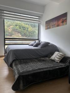 a bed in a bedroom with a large window at Aparta estudio Zona Norte Bogotá in Bogotá +39 photos