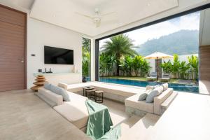 a living room with a couch and a tv and a pool at Eden Escape Naiyang Beach in Phuket Town
