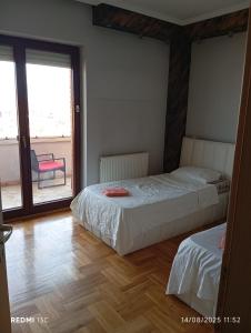 a bedroom with two beds and a window with a chair at Bus Station Flat 32 in Prizren