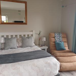 a bedroom with a bed and a mirror and a chair at Naizna Stays in Knysna