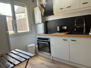 a kitchen with white cabinets and a sink and a stove at Loc MI in Carentan