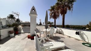 patio z białymi krzesłami, stołem i parasolem w obiekcie VISION RELAX HOME w mieście Playa del Ingles