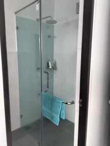 a shower with a glass door with a blue towel at Santorini Resort Apartment 3 Bed rooms- Negombo Beach & Airport in Negombo