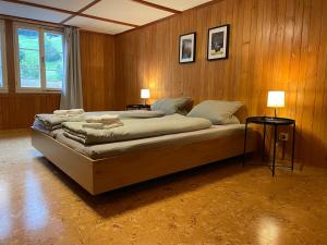 a large bed in a room with wooden walls at Apartment HasliView in Innertkirchen