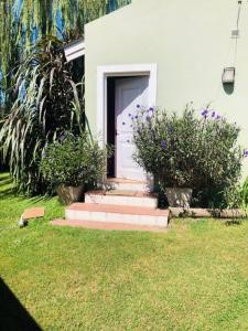 a house with a white door and some bushes at La Casita in San Antonio de Areco +2 photos