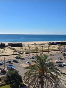 a parking lot with a palm tree and the beach at Monte G Sea View in Monte Gordo